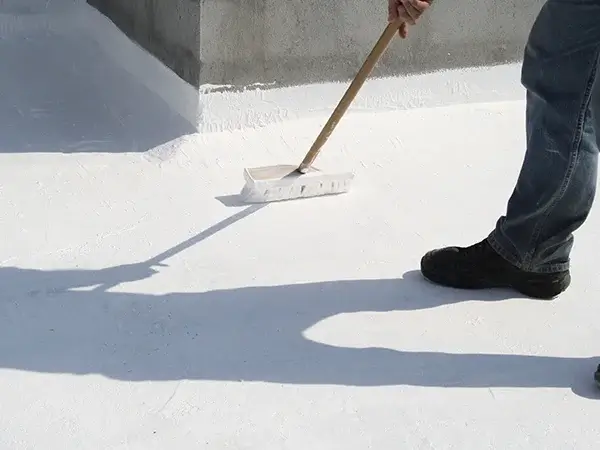 Roofer applying white roof coating